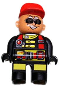 Duplo Male Action Wheeler - Male Duplo figure in Action Wheeler outfit with black legs, yellow patches, red straps, sunglasses, and a red cap - 4555pb182
