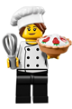 Female chef with black legs, hair in a bun, open mouth smile, and "LEGO HOUSE Home of the Brick" on back - chef026