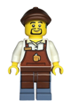 Male barista wearing a reddish brown apron with cup and name tag, sand blue legs, reddish brown flat cap, and hearing aid - twn473